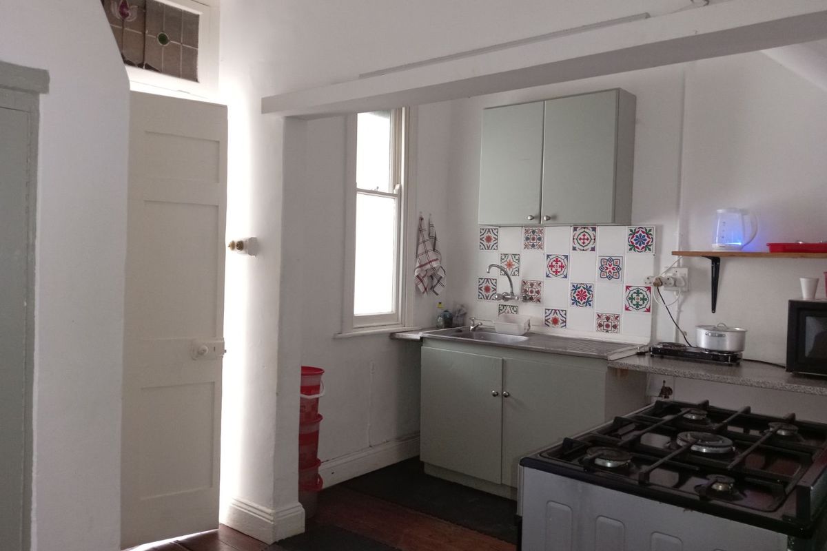 A compact kitchen area featuring built-in cabinetry, a decorative tiled backsplash, a stainless steel sink, and a gas stove.