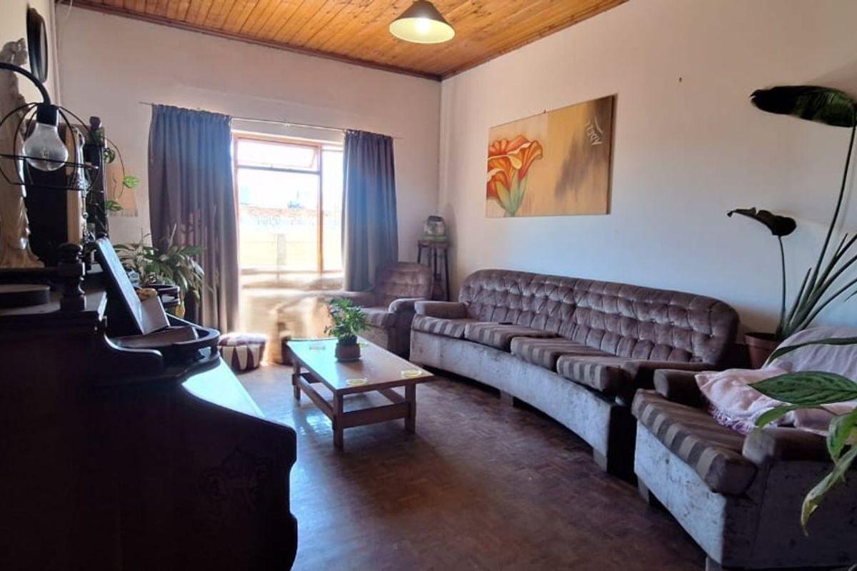 A living room featuring timber ceiling paneling and parquet flooring, providing a traditional foundation for potential interior updates.