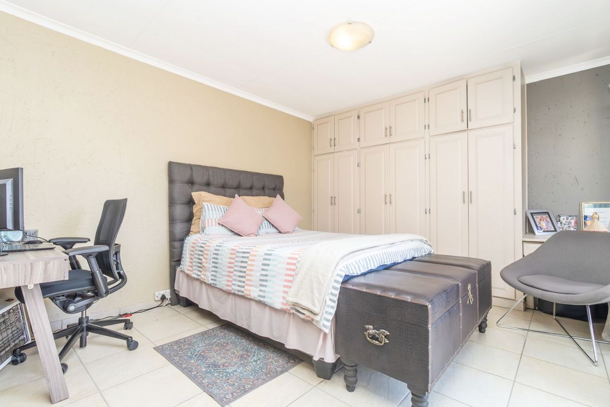 A functional bedroom featuring built-in floor-to-ceiling cabinetry, tiled flooring, and neutral wall finishes, providing ample storage and a comfortable living space.