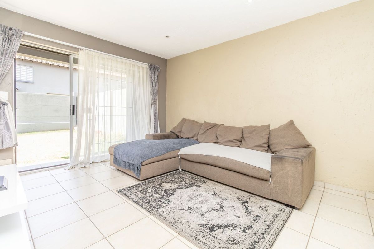 A living room featuring tiled flooring and a large sliding glass door providing access to the outdoor area.