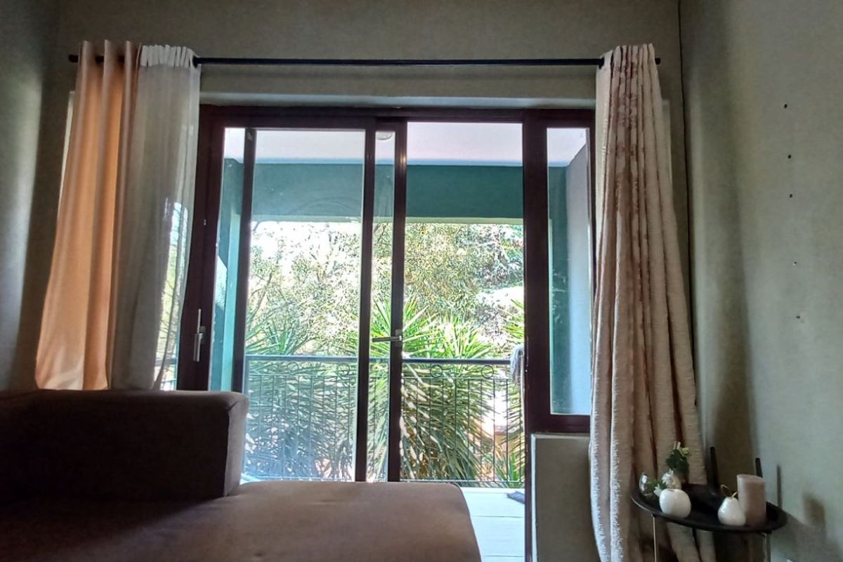 A bedroom featuring sliding glass doors that open onto a private balcony, providing natural light and views of the surrounding greenery.