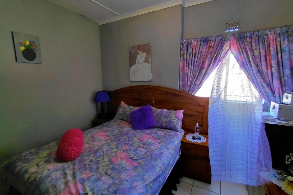 A bedroom featuring tiled flooring, a window with security bars, and a ceiling vent.