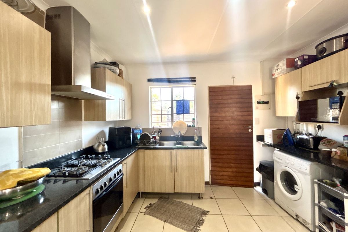 Functional kitchen featuring light wood cabinetry, dark granite countertops, built-in gas stove with extractor fan, and integrated laundry plumbing.