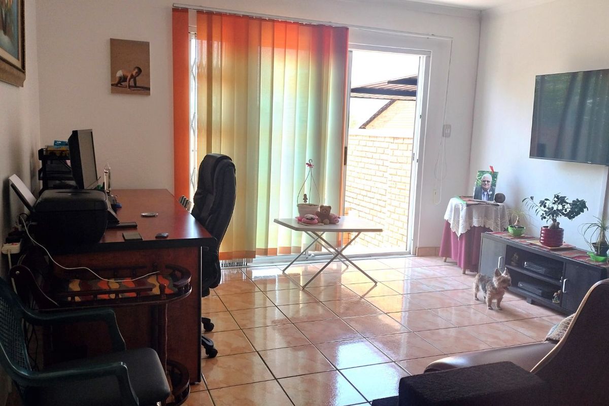 A living room featuring tiled flooring and a sliding glass door providing access to an outdoor area.