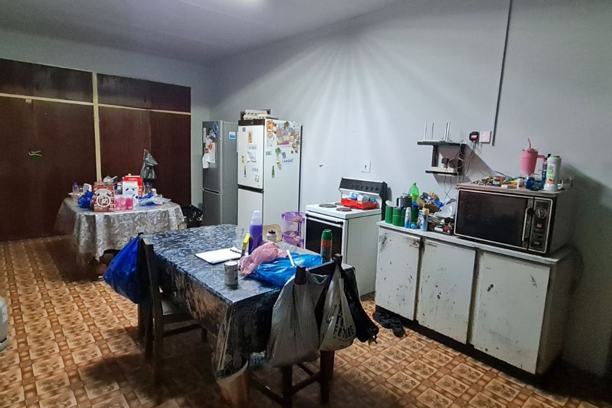 A dated kitchen area featuring basic cabinetry, a freestanding stove, and patterned floor tiles, offering potential for a modern renovation.