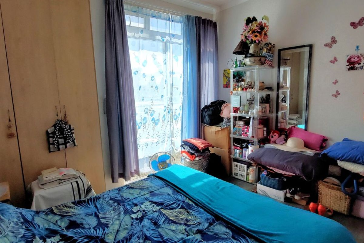 A bedroom featuring built-in wooden wardrobes and a sliding glass door providing access to an outdoor area.