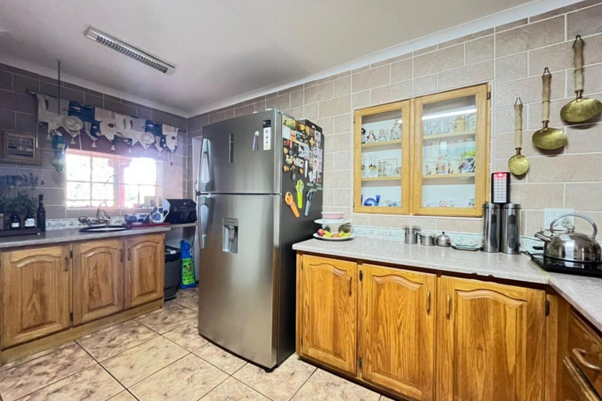 A functional kitchen featuring wooden cabinetry, tiled walls, and tiled flooring, providing a traditional layout with ample counter space.