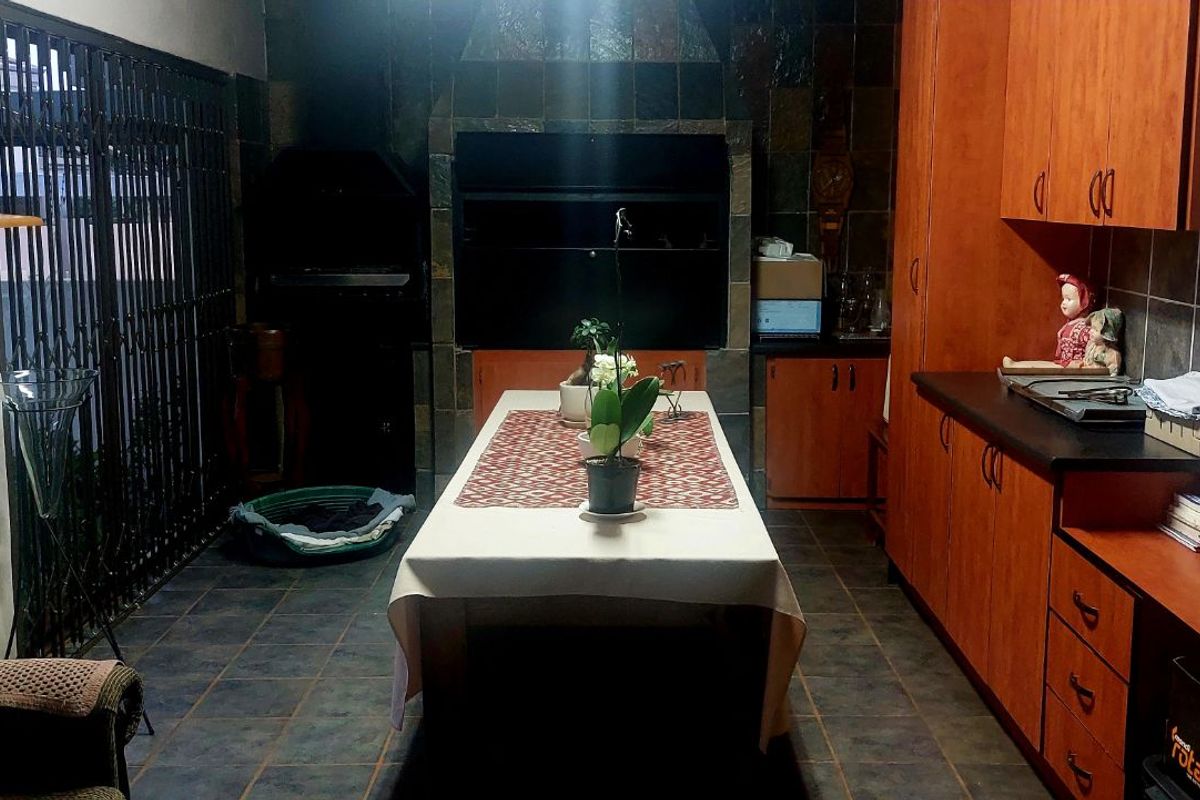 An indoor entertainment area featuring a built-in braai, tiled flooring, and wooden cabinetry, providing a functional space for dining and social gatherings.