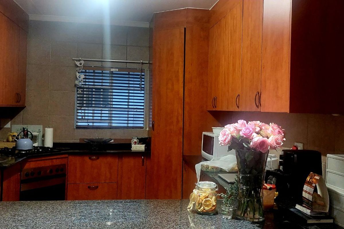 A functional kitchen featuring wood-veneer cabinetry, granite countertops, and a built-in oven with a gas hob.