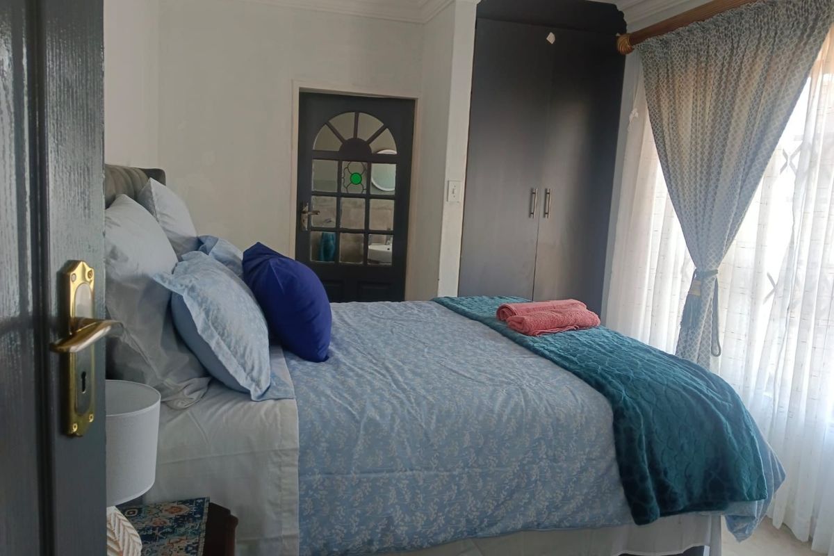 A bedroom featuring built-in cupboards and an adjacent en-suite bathroom with a decorative glass-paneled door.