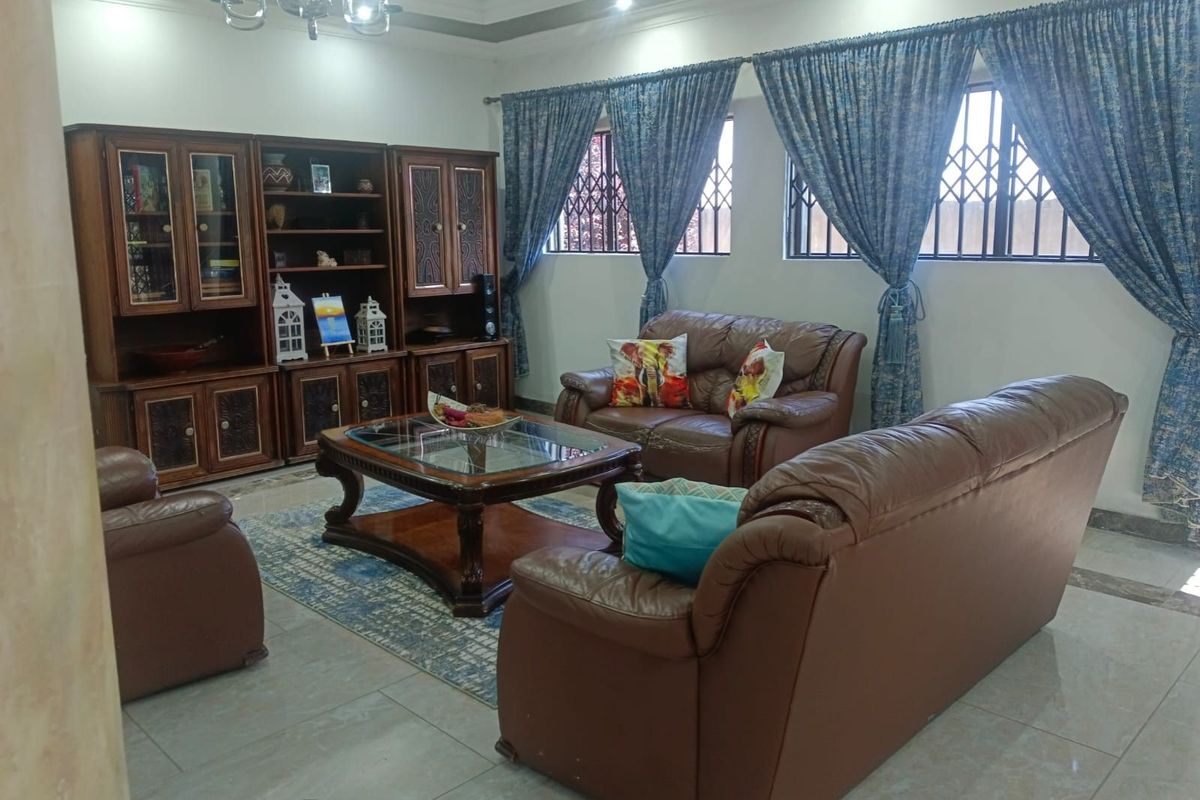 A spacious living room featuring tiled flooring, recessed ceiling lighting, and security bars on the windows.