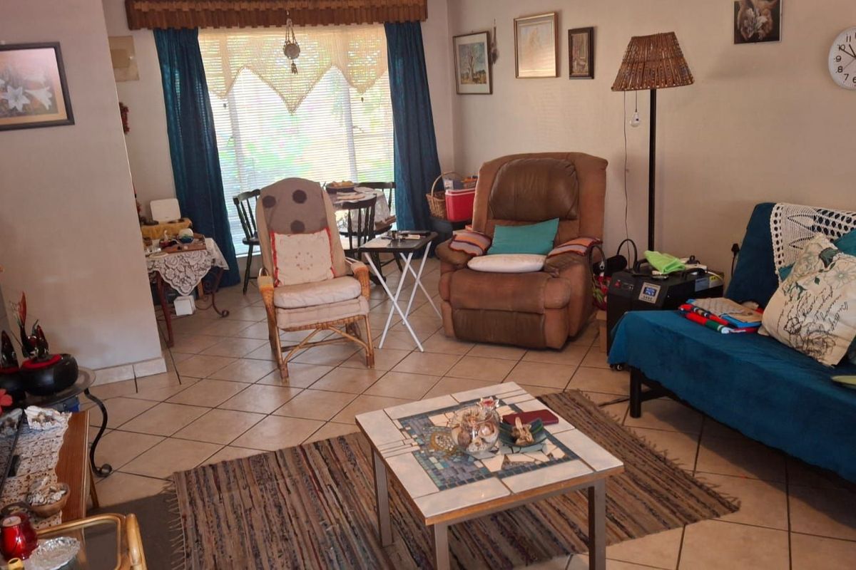 A living room area featuring ceramic floor tiles and a large window with natural light, providing a functional and comfortable living space.