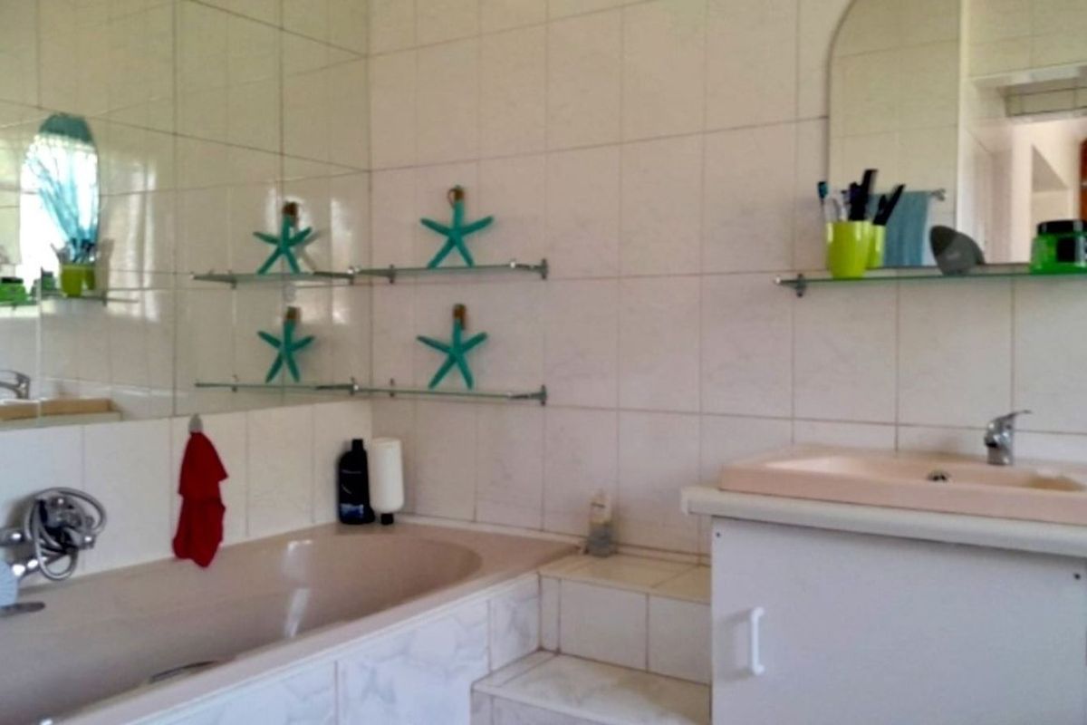 A dated bathroom featuring a built-in bathtub, a vanity sink, and wall-to-wall tiling.