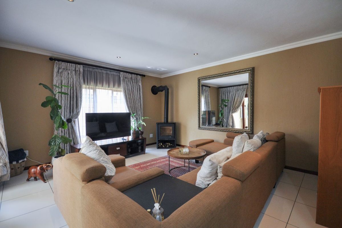 A comfortable living room featuring tiled flooring, a built-in wood-burning fireplace, and large windows with curtains.