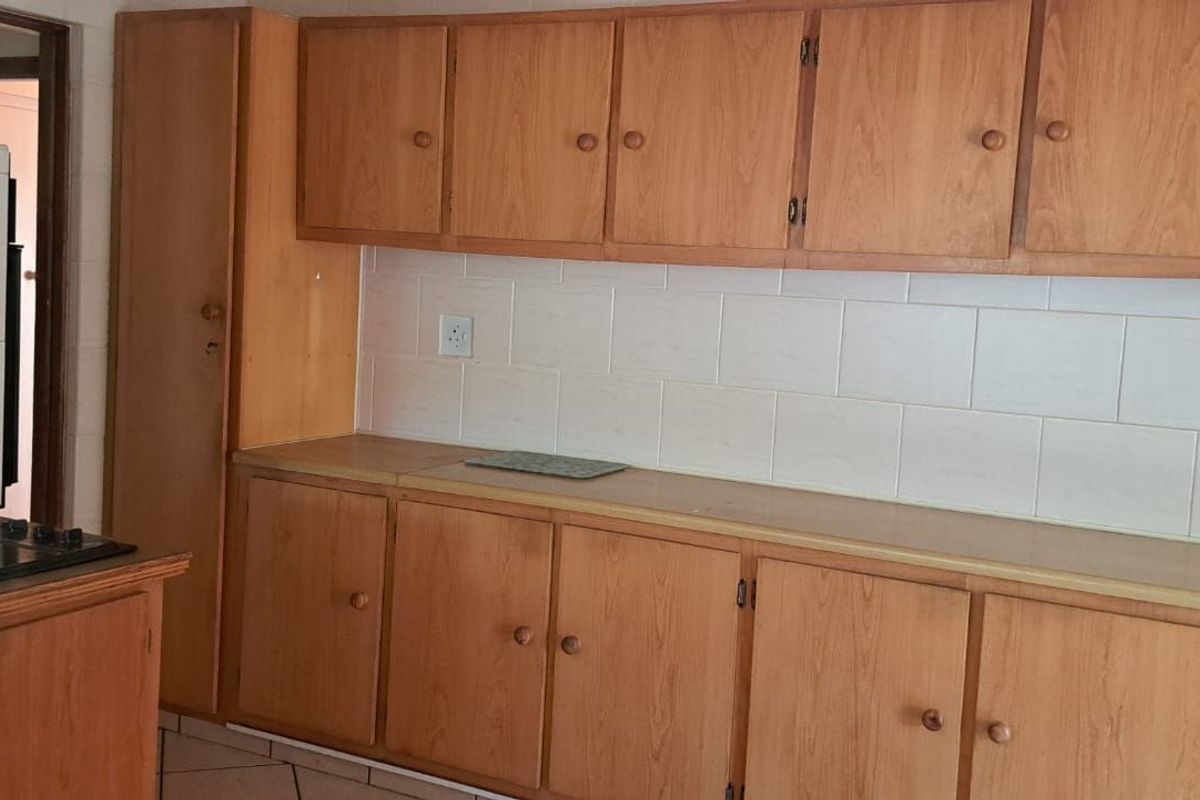 A functional kitchen featuring wooden cabinetry, tiled backsplash, and a built-in electric hob, offering a classic layout ready for modernization.