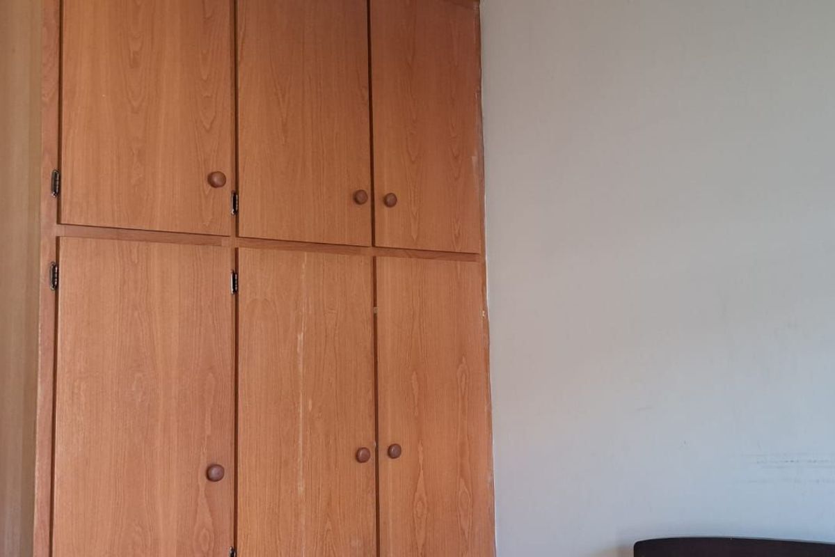 A bedroom featuring built-in wooden cabinetry with ample storage space and neutral wall finishes.