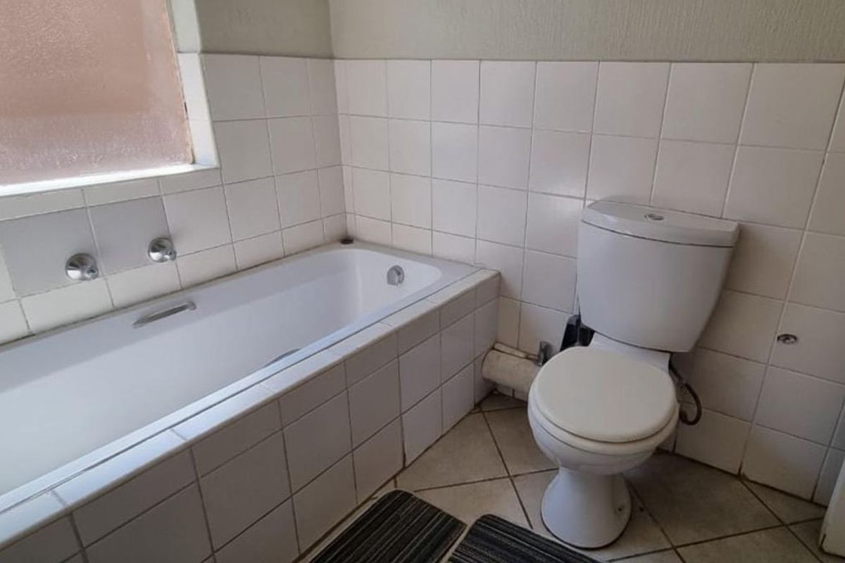 A functional bathroom featuring a built-in bathtub with wall-mounted taps and a standard white toilet.