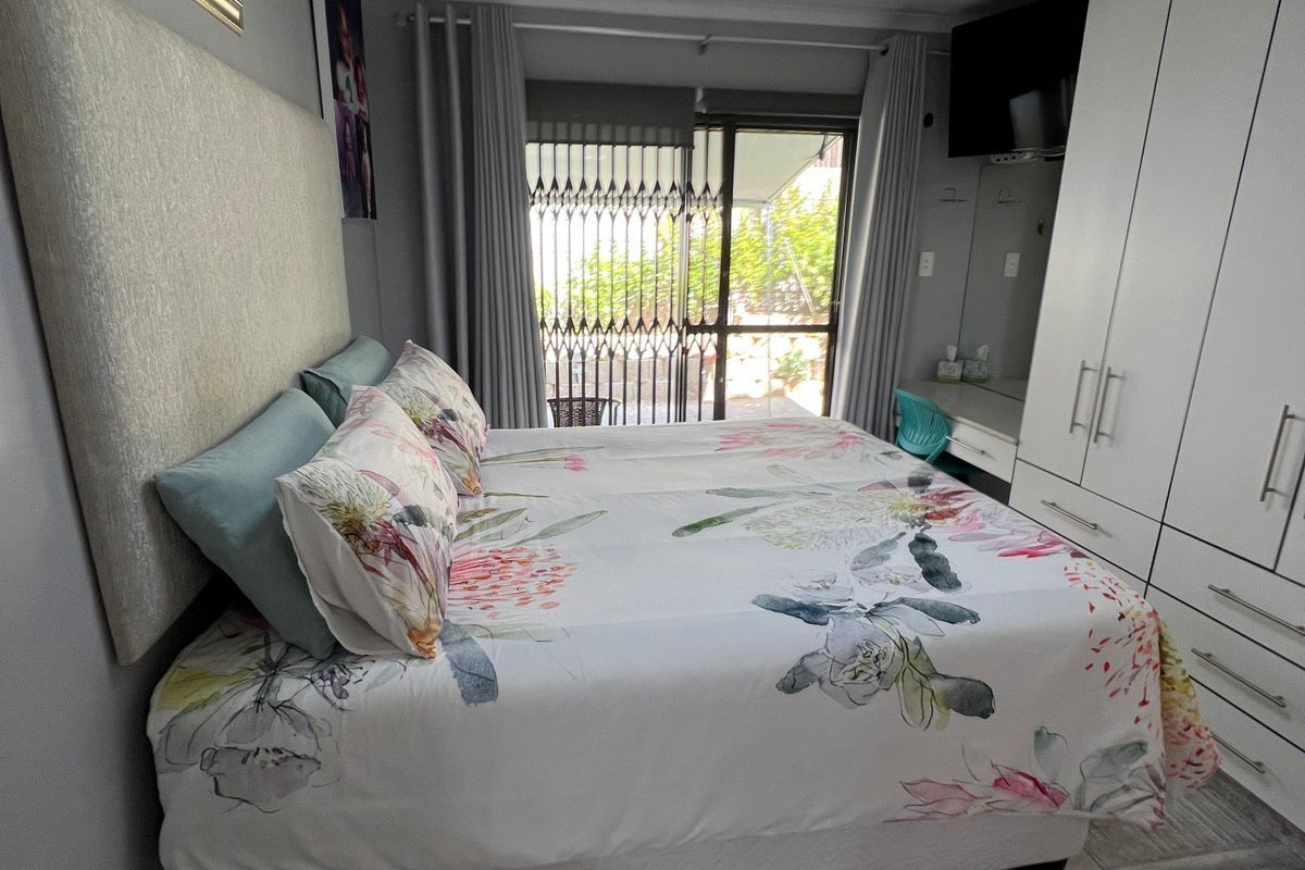 A well-maintained bedroom featuring built-in wardrobes, a ceiling fan, and sliding glass doors leading to an outdoor area.