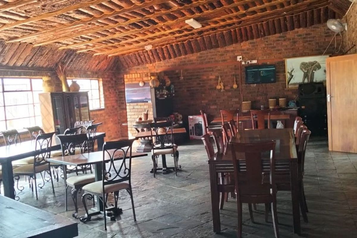 Spacious rustic entertainment area featuring exposed brick walls, a high timber-beamed ceiling, and slate flooring, ideal for large gatherings.