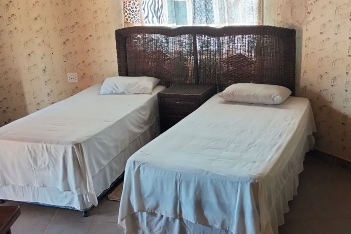 A bedroom featuring tiled flooring and patterned wall finishes, providing a functional sleeping space.