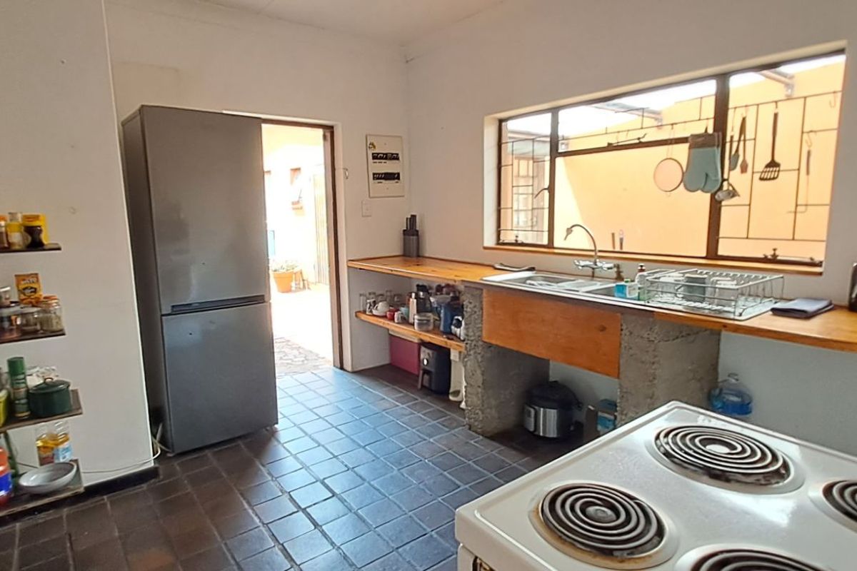 A functional kitchen featuring a concrete-based sink unit, wooden countertops, tiled flooring, and direct access to an outdoor area.