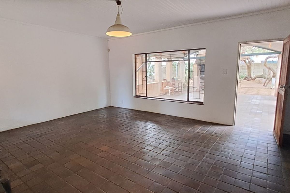 A spacious, empty living room featuring tiled flooring, a wood-burning stove, and direct access to an outdoor patio area.
