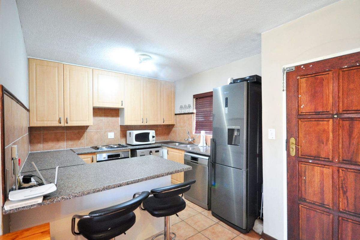 Functional kitchen featuring light wood cabinetry, granite-look countertops, tiled backsplash, and integrated appliance spaces, including a breakfast bar area.