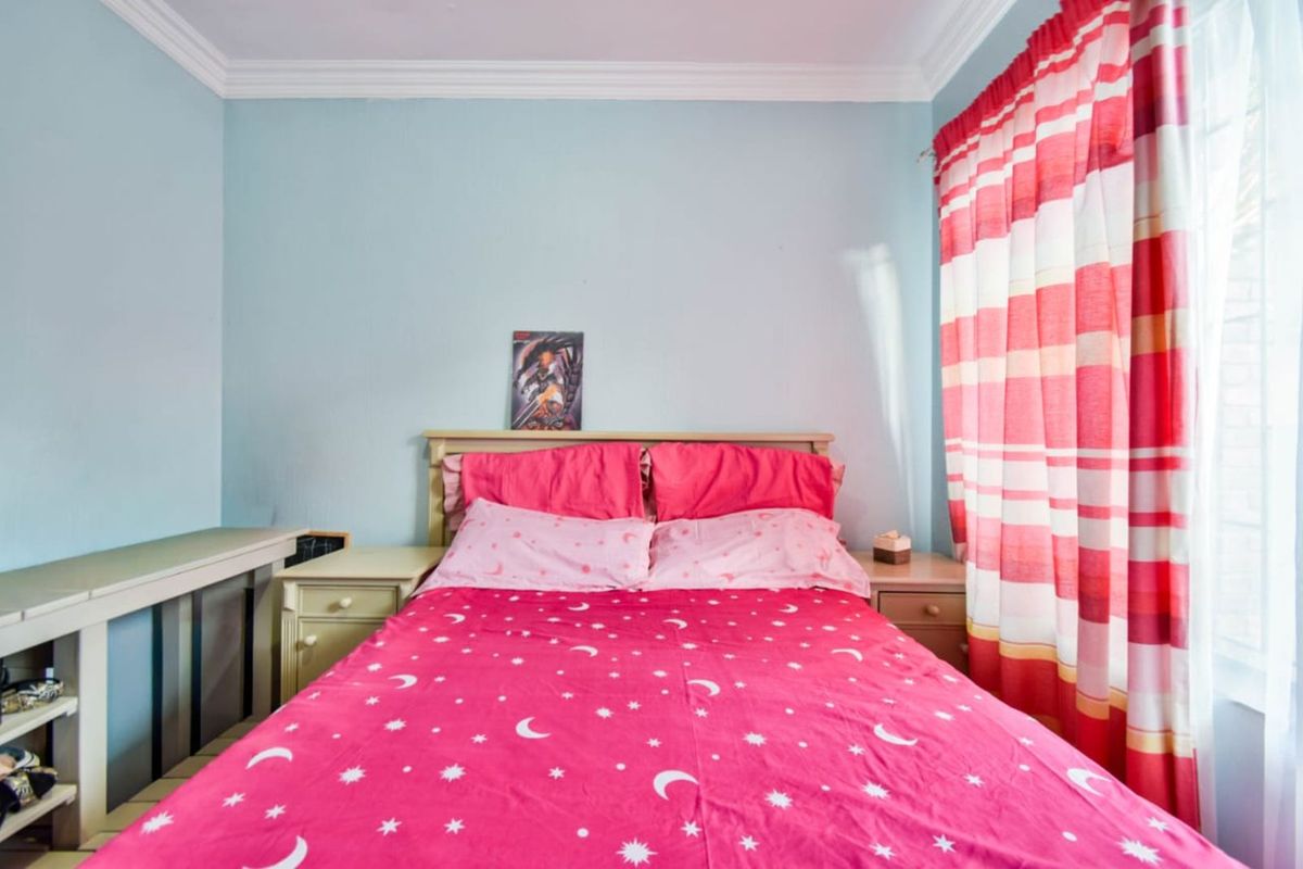 A bedroom featuring crown molding and a built-in desk unit, providing a functional space with natural light.