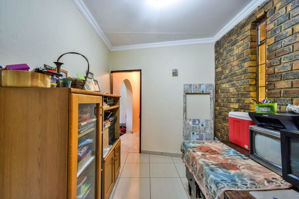A functional interior space featuring tiled flooring, a decorative brick feature wall, and an arched doorway leading to adjacent rooms.