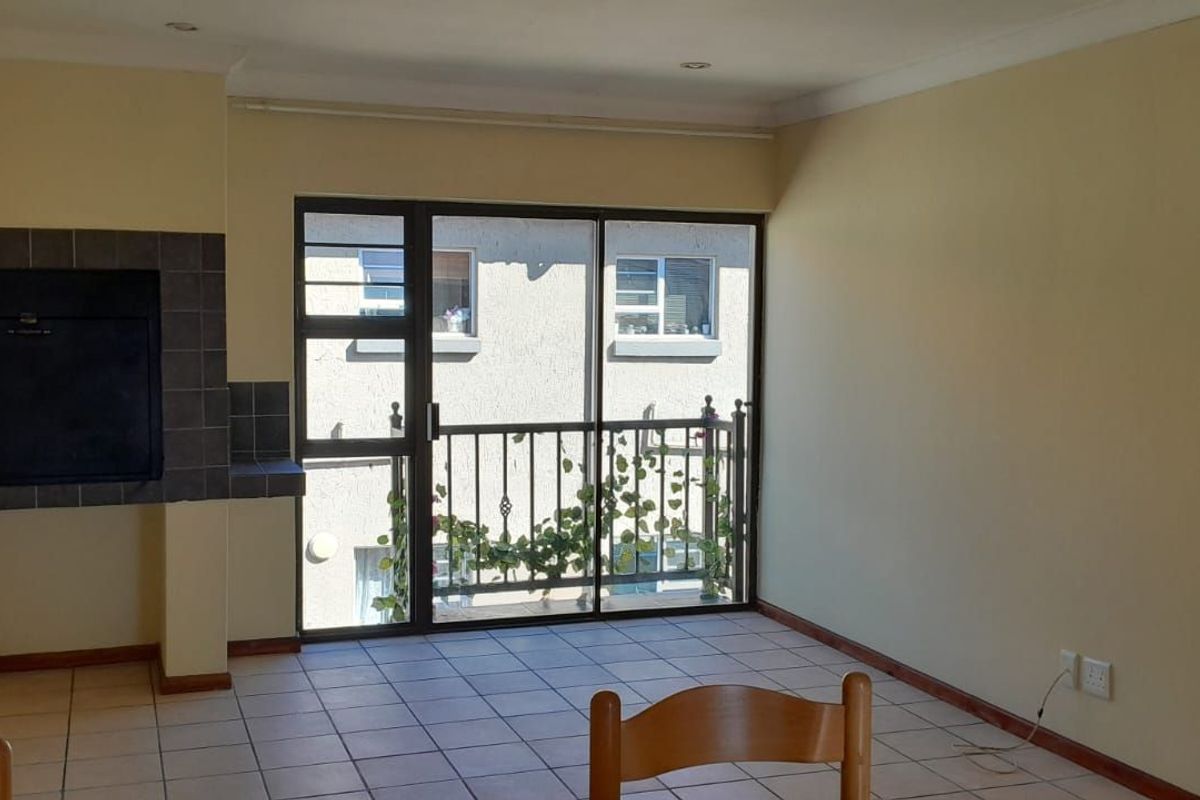 A spacious living area featuring tiled flooring, a built-in fireplace, and sliding glass doors leading to a private balcony.