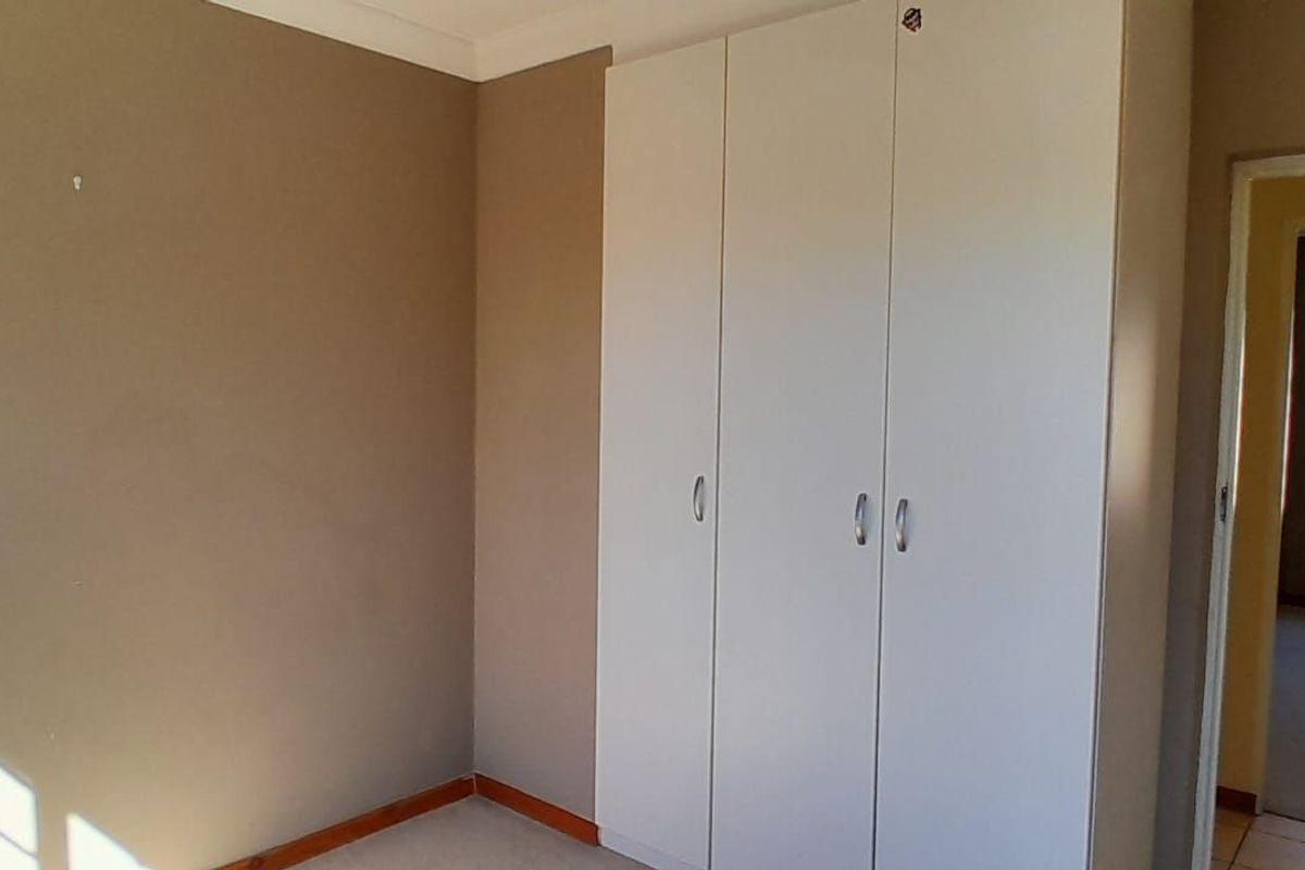 A bedroom featuring built-in white cabinetry and neutral wall tones, with a view into an adjacent room through the doorway.