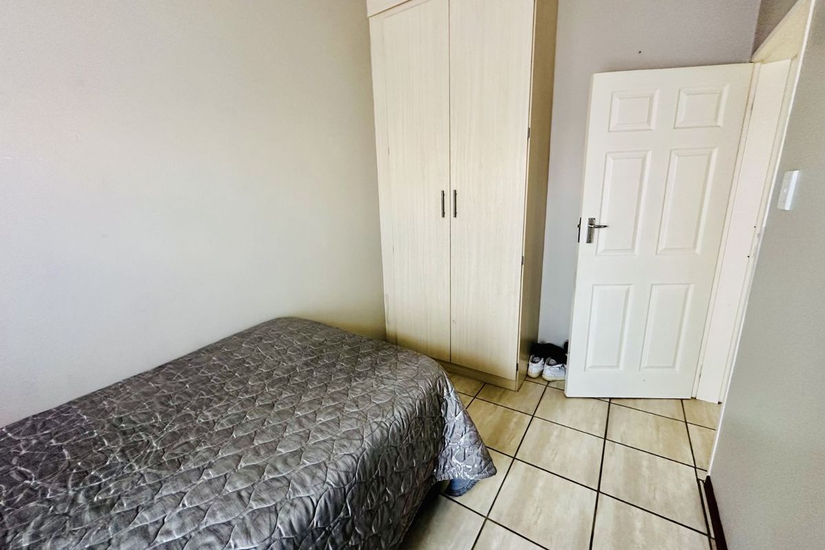 A bedroom featuring tiled flooring and a built-in wardrobe.