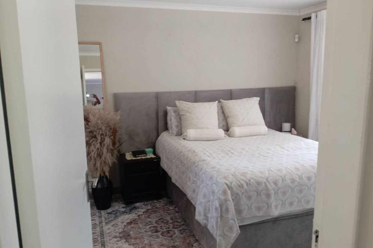 A bedroom featuring a neutral color palette, coved ceiling, and a built-in headboard wall panel.