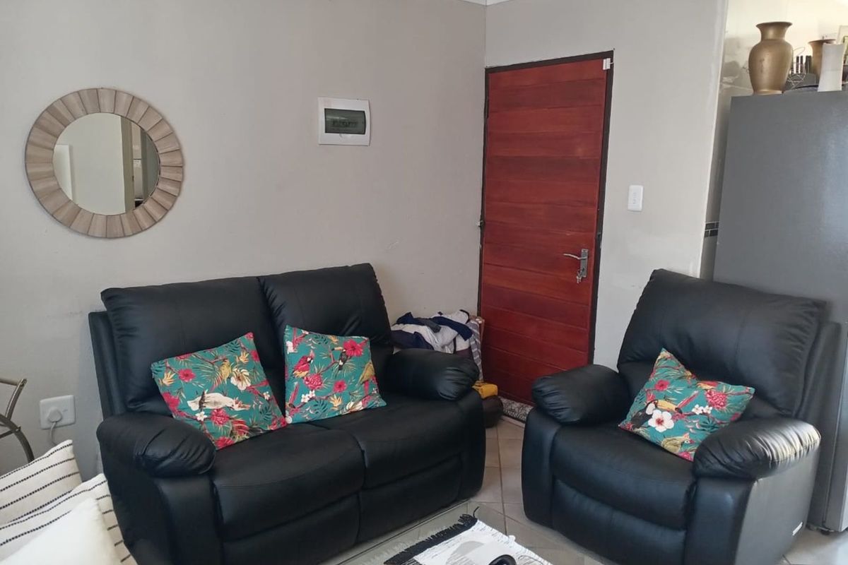 A functional living room area featuring tiled flooring and a solid timber entrance door.