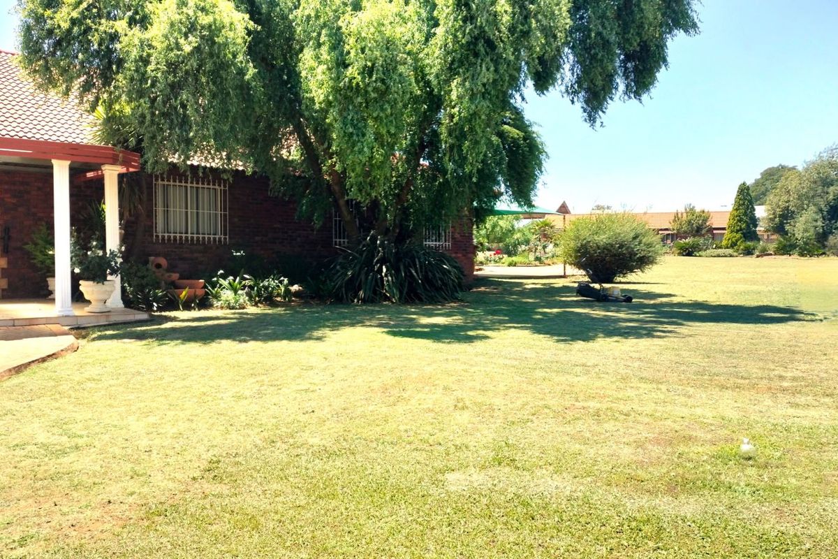 A view of the farm property featuring a brick exterior, a covered patio area, and expansive green lawn space.