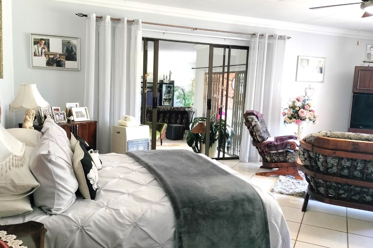 Spacious bedroom featuring tiled flooring, ceiling fan, and sliding glass doors providing access to an adjoining living area.