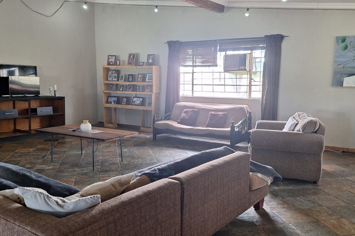 Spacious living area featuring rustic slate tile flooring and exposed timber ceiling beam, providing a comfortable and functional family space.