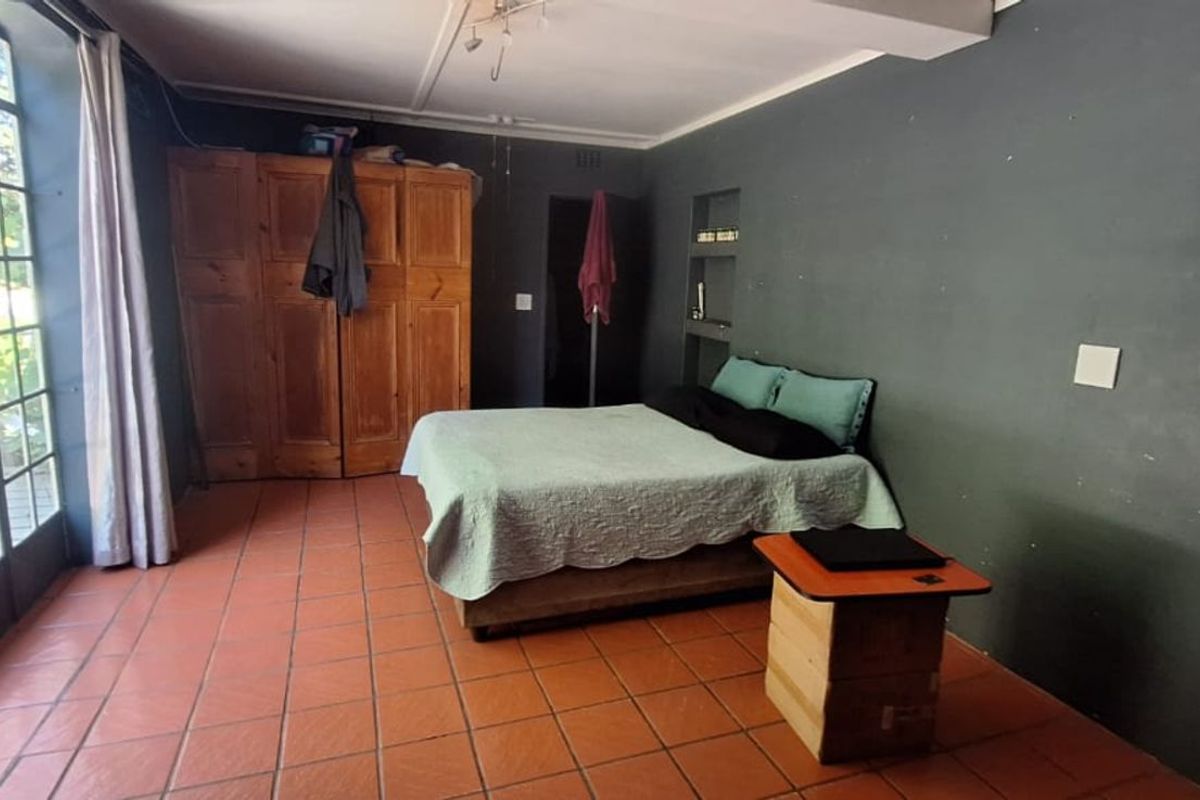 Spacious bedroom featuring terracotta floor tiles, built-in wooden cabinetry, and large glass doors providing direct access to the outdoor area.