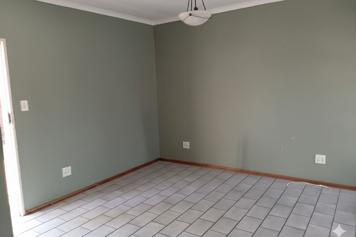 A vacant room featuring neutral green walls, tiled flooring, and a central ceiling light fixture.