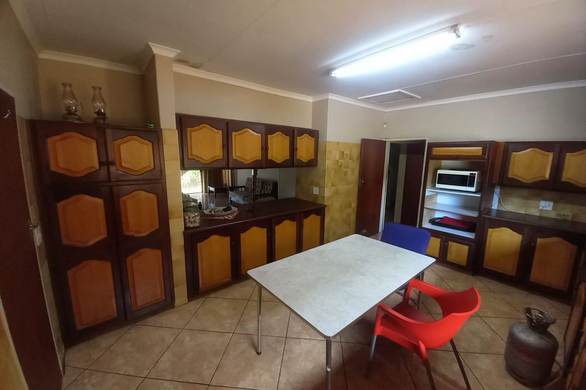 A functional kitchen area featuring extensive built-in wooden cabinetry, tiled flooring, and a dedicated space for meal preparation.