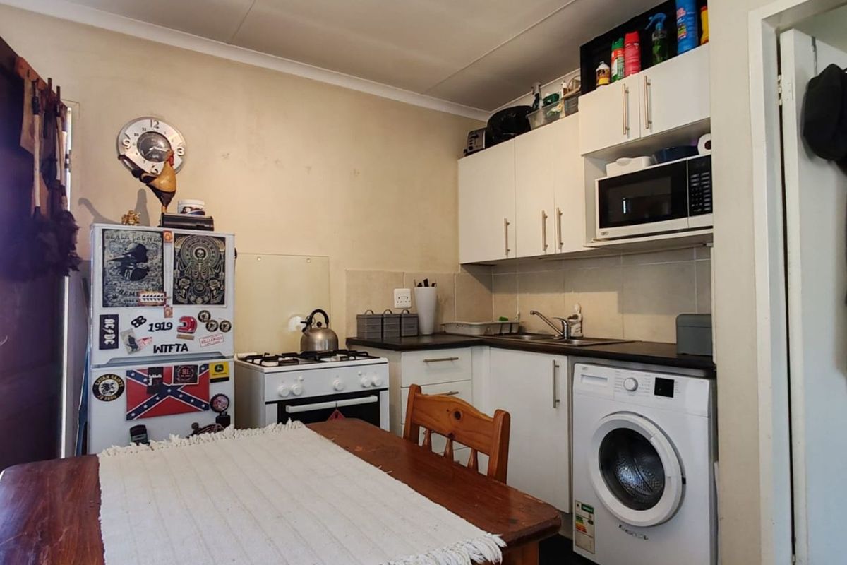 Compact kitchen featuring white cabinetry, integrated sink, built-in microwave, and space for a washing machine, with tiled flooring and functional layout.