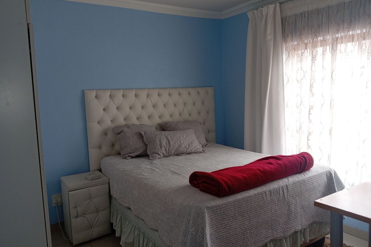 A bedroom featuring blue painted walls, crown molding, and a window with curtains.