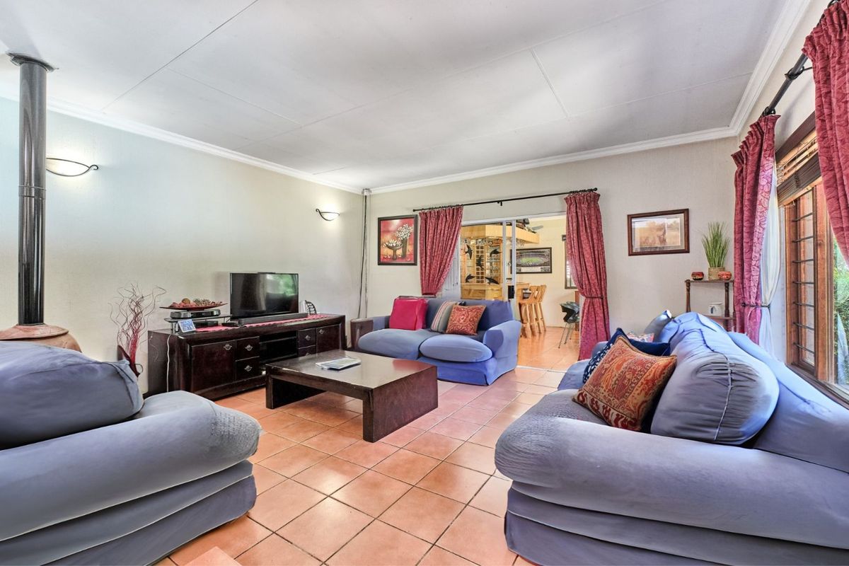 Spacious living room featuring terracotta floor tiles and a built-in fireplace, with sliding door access to an adjacent dining area.