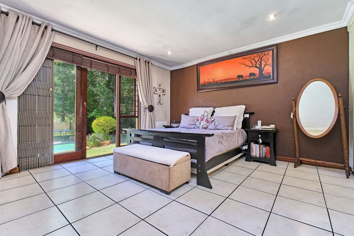 Spacious bedroom featuring tiled flooring and large sliding glass doors providing direct access to the garden and pool area.