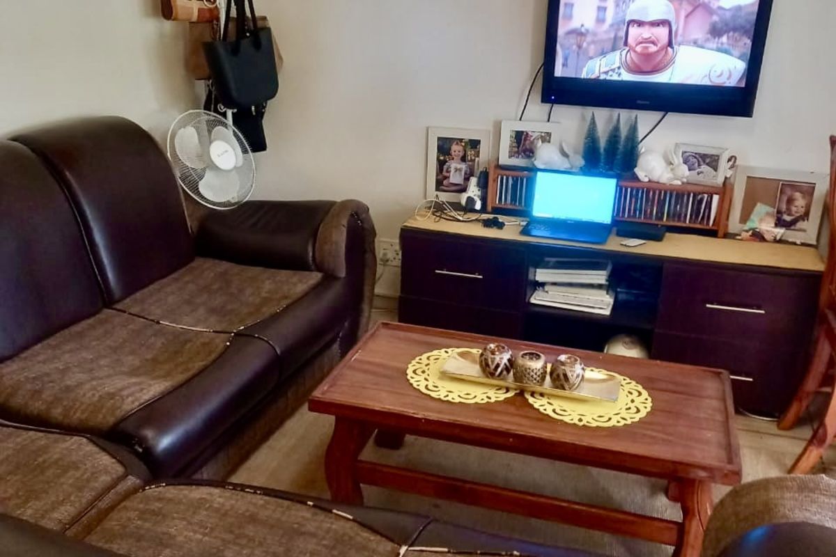 A living room area featuring a wall-mounted television and laminate flooring.
