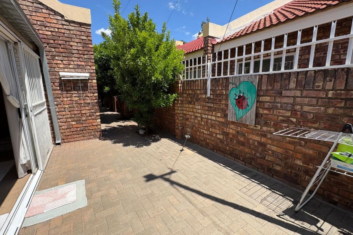 A private rear courtyard featuring paved flooring, enclosed by face-brick walls and a secure sliding door entrance to the main living area.