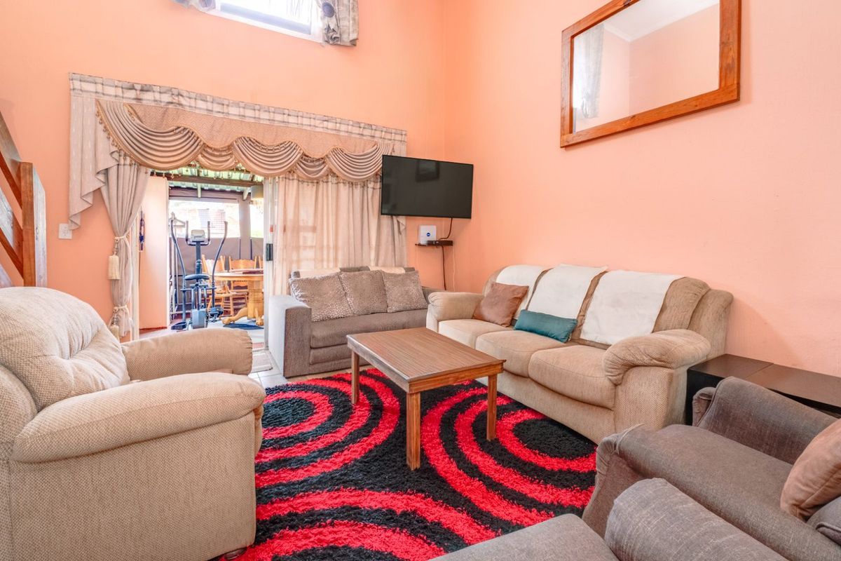 A spacious living room with high ceilings, featuring large sliding glass doors that open onto a patio area.