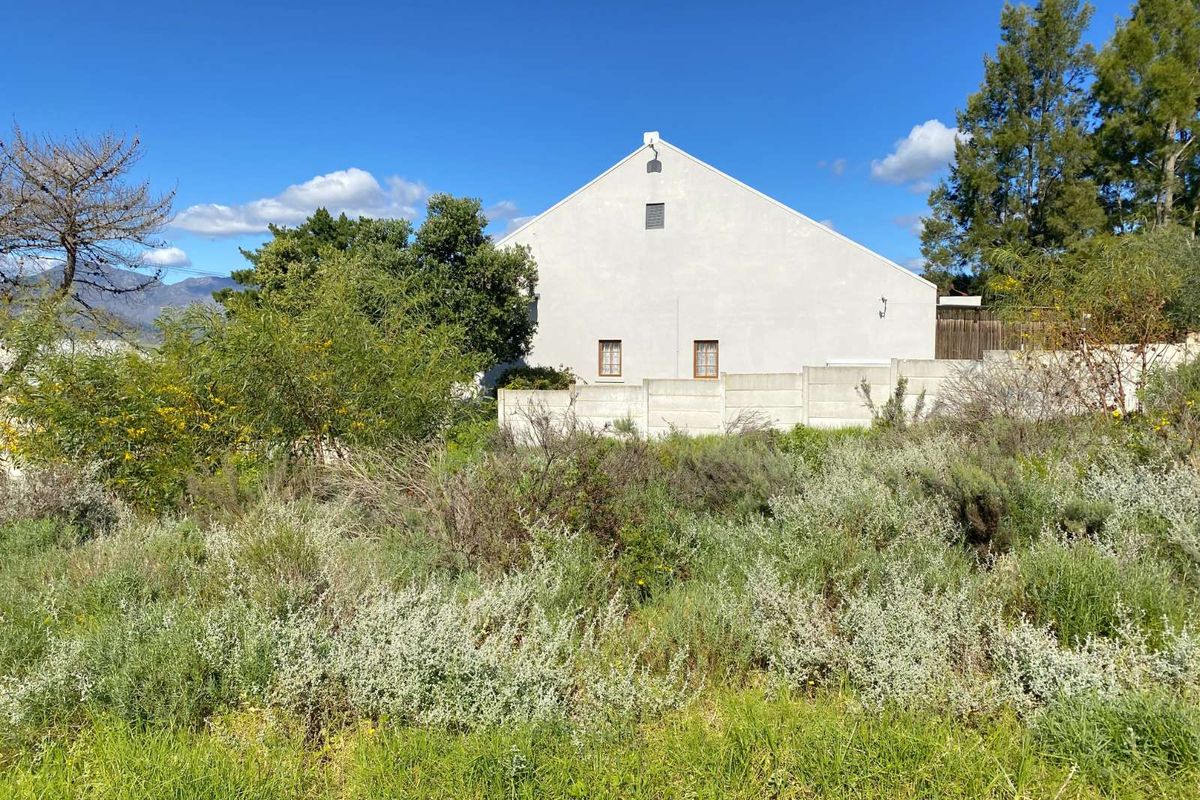 A view of the rear elevation of a residential property, featuring a white gable wall and a precast concrete boundary wall.