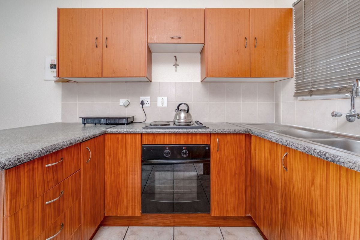 Compact kitchen featuring wood-look cabinetry, granite-style countertops, a built-in oven, and a hob, providing a functional workspace.