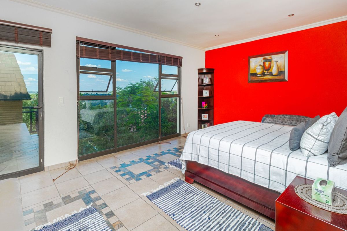 Spacious bedroom featuring large sliding glass doors with scenic views, tiled flooring, and a bold accent wall.